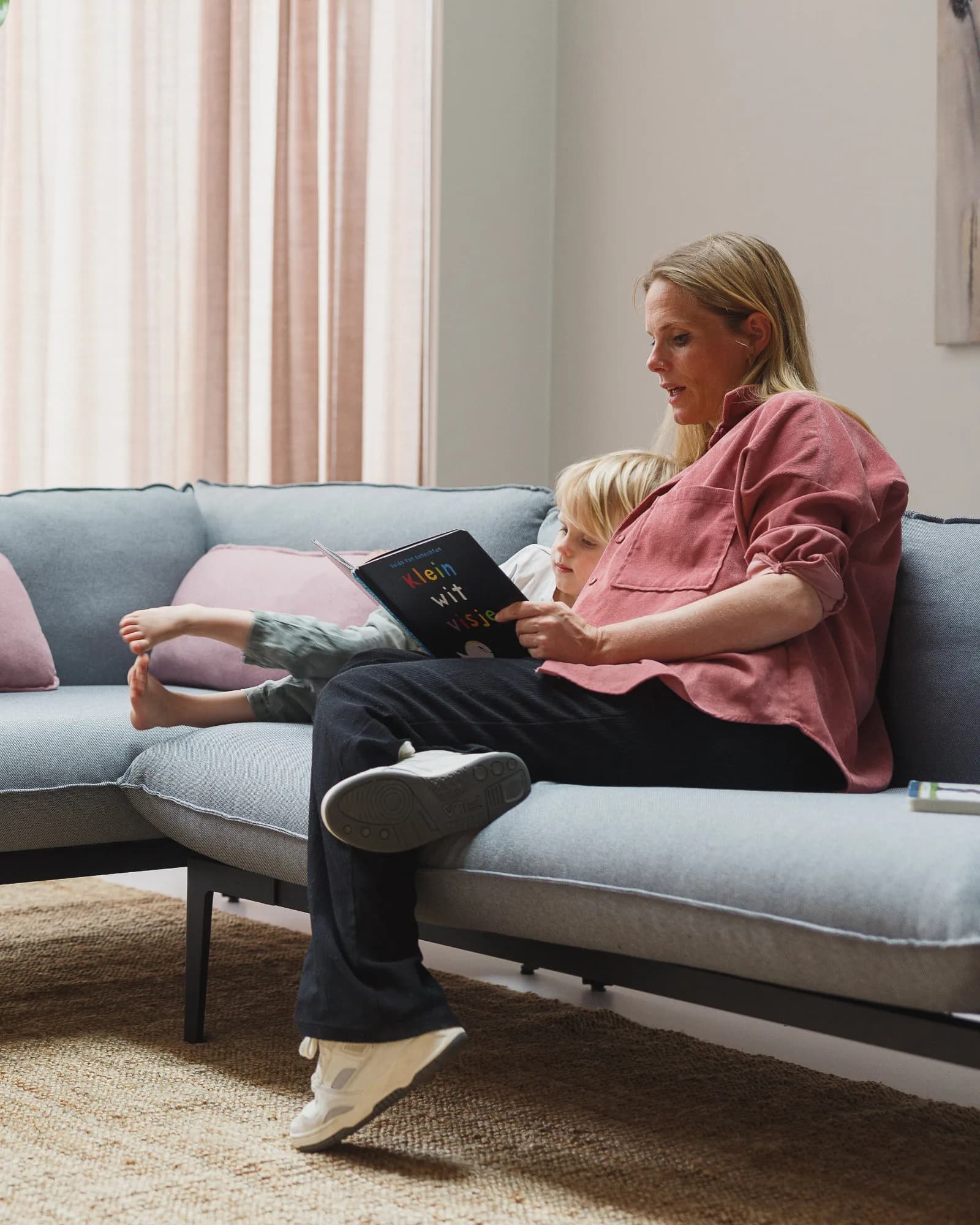 Mother and child reading book on sofa
